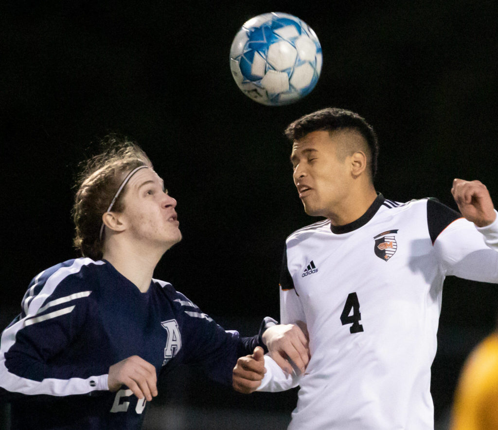 Arlington’s Jack Machovina watches Monroes Rafael Garnica heads the ball Friday evening at Arlington High School in Arlington, Washington on March 18, 2022. (Kevin Clark / The Herald)
