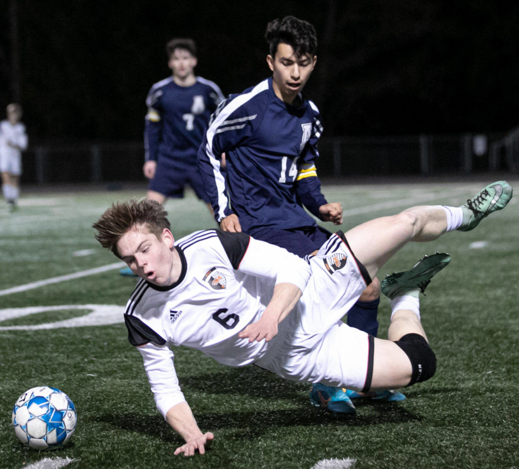 Monroe’s Owen Skurdal is tripped by Arlington’s Emmanuel Escalante Friday evening at Arlington High School in Arlington, Washington on March 18, 2022. (Kevin Clark / The Herald)
