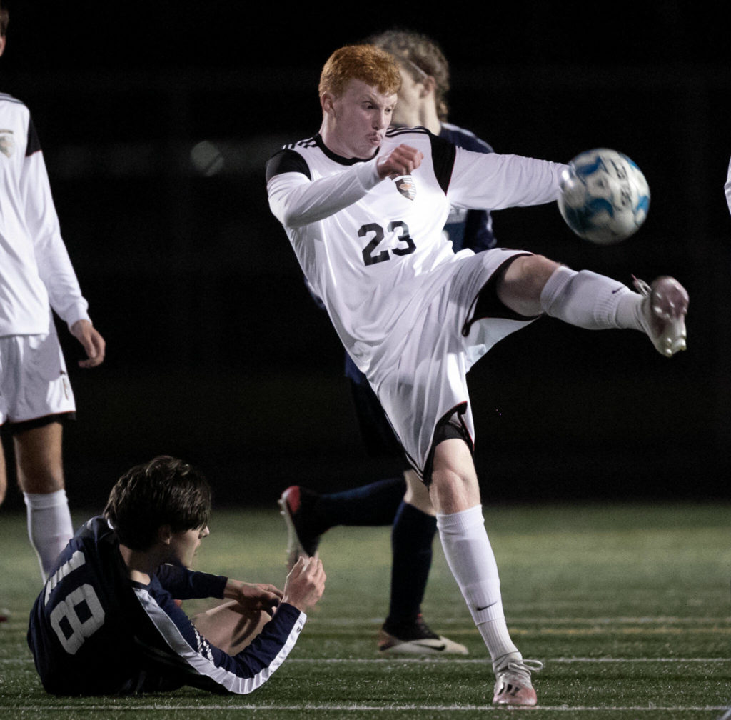 Monroe’s Cody Duncan kicks the ball free with Arlington’s Lucas Frazier Friday evening at Arlington High School in Arlington, Washington on March 18, 2022. (Kevin Clark / The Herald)

