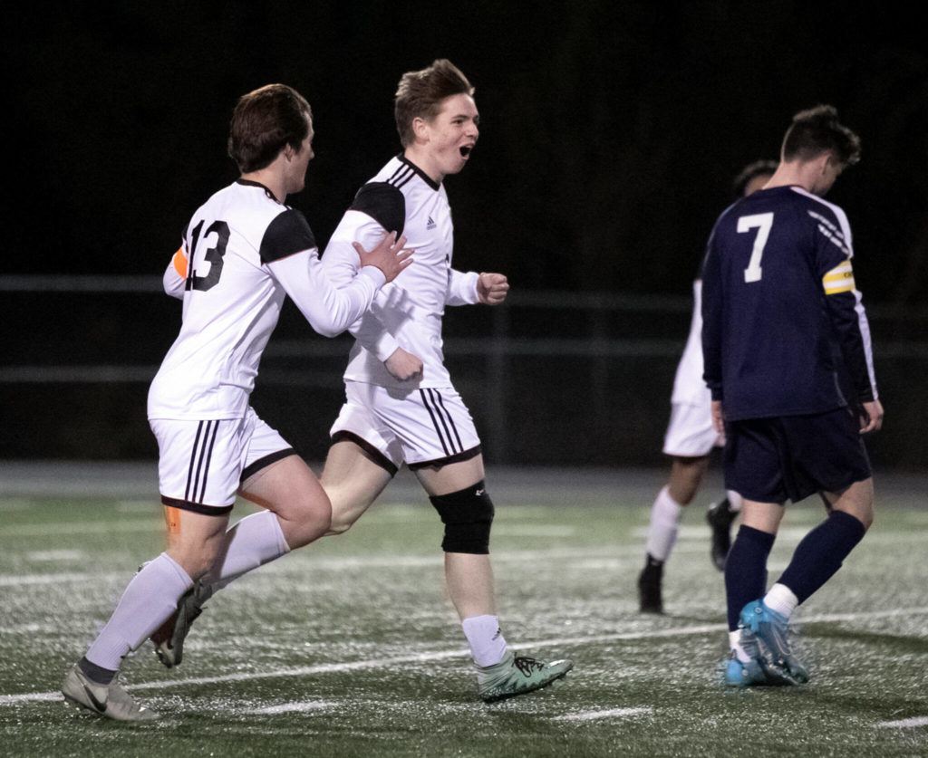 Monroe’s Owen Skurdal, center, celebrates a goal with Monroe’s Joshua Gunter, left, Friday evening at Arlington High School in Arlington, Washington on March 18, 2022. (Kevin Clark / The Herald)
