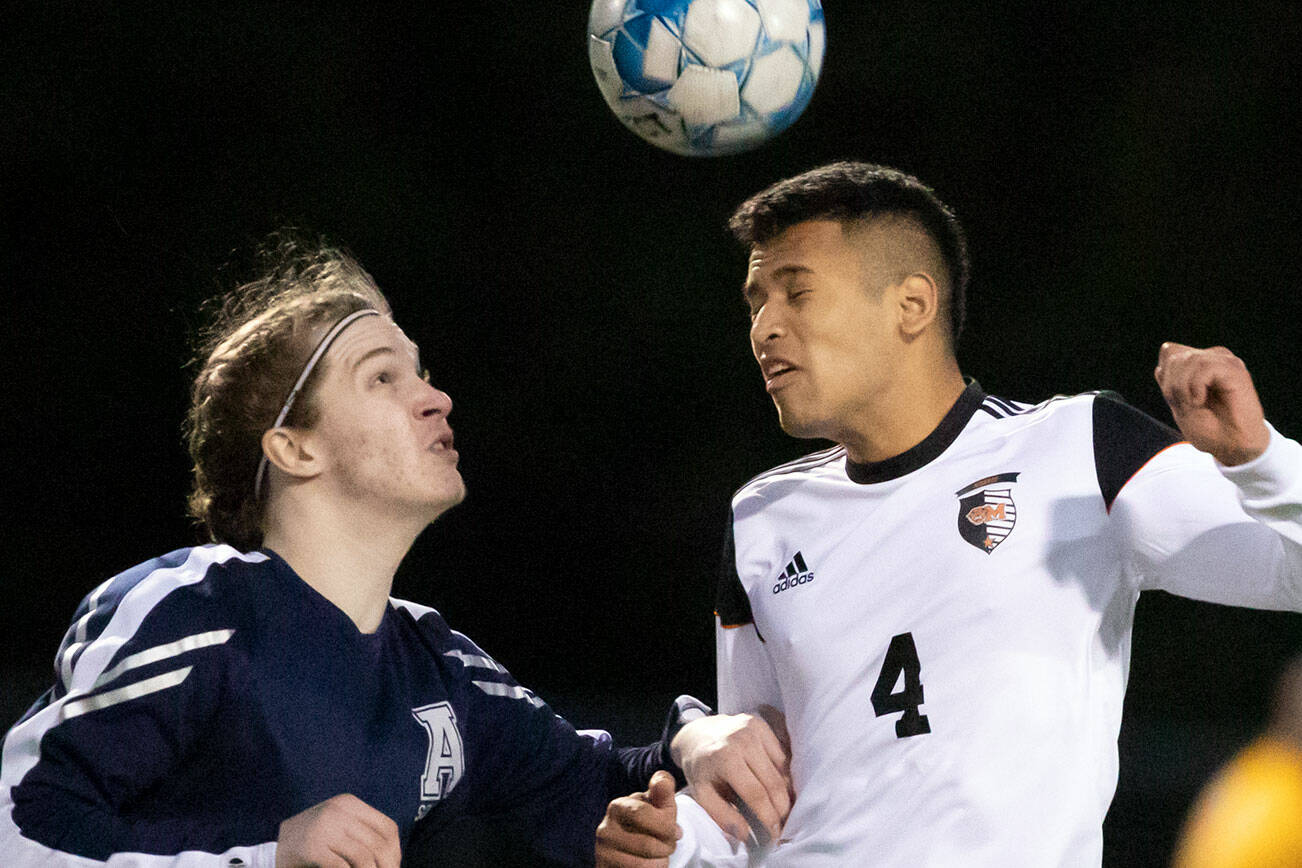 Arlington's Jack Machovina watches Monroe's Rafael Garnica heads the ball Friday evening at Arlington High School in Arlington, Washington on March 18, 2022. (Kevin Clark / The Herald)