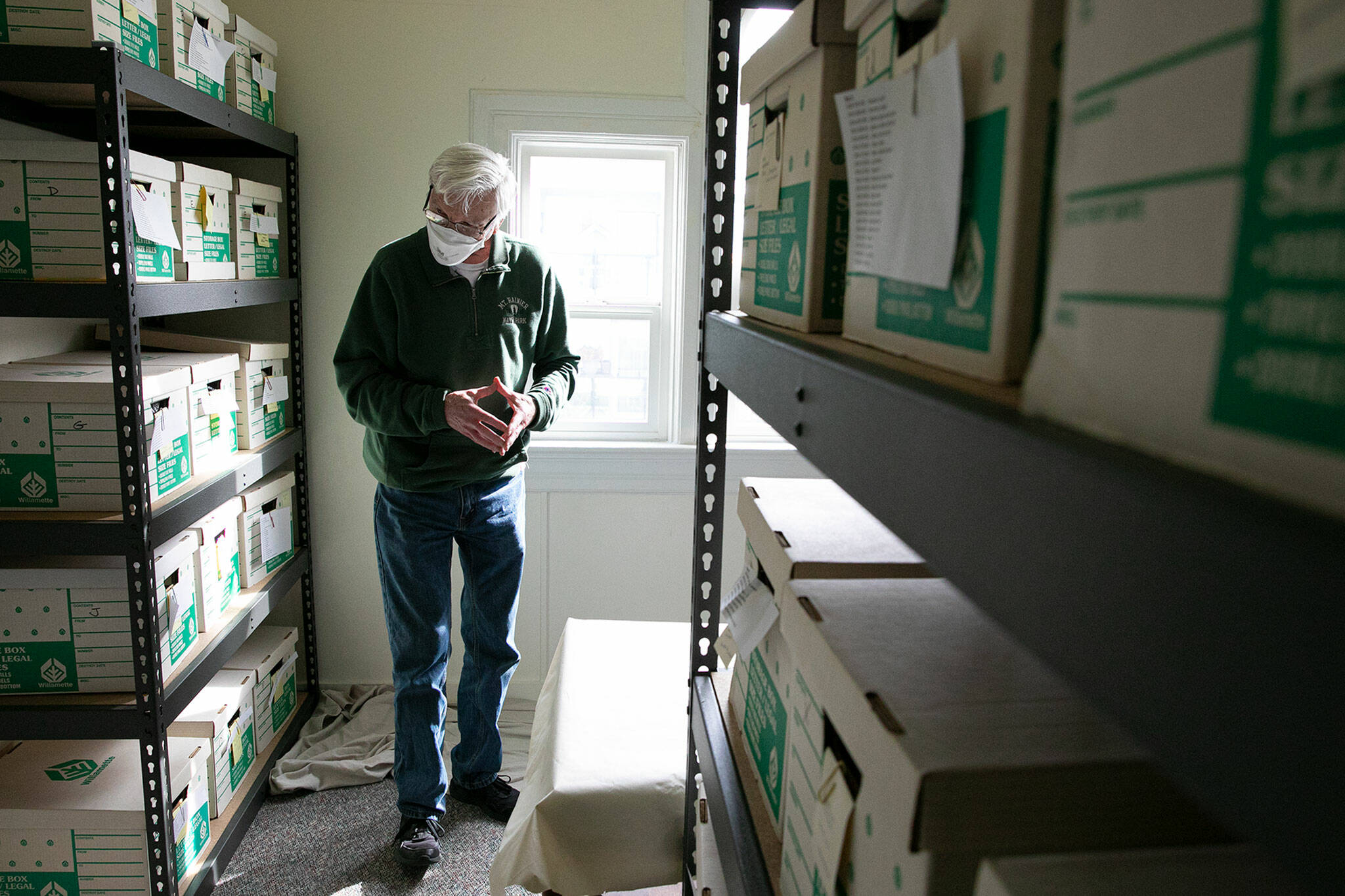 Mukilteo Historical Society volunteer Peter Anderson stands in an archive of historic objects that have been filed away at the Mukilteo Lighthouse. (Ryan Berry / The Herald)