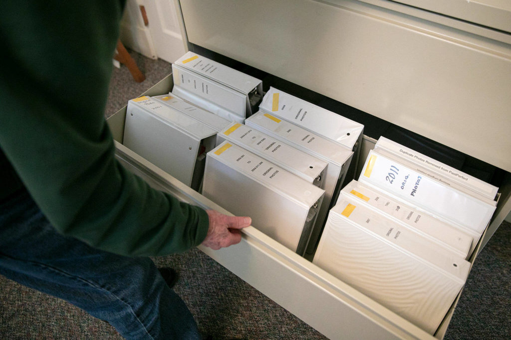 Mukilteo Historical Society volunteer Peter Anderson rifles through binders of images from the town’s history. (Ryan Berry / The Herald)
