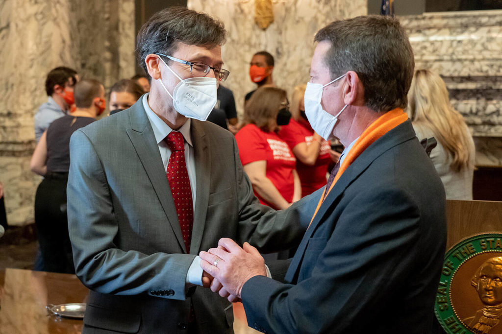 Washington Attorney General Bob Ferguson (left) speaks with Paul Kramer at the signing of bills aimed at reducing gun violence Wednesday in Olympia. Kramer’s son Will was injured in a 2016 mass shooting in Mukilteo that left three people dead. (Washington State Attorney General)
