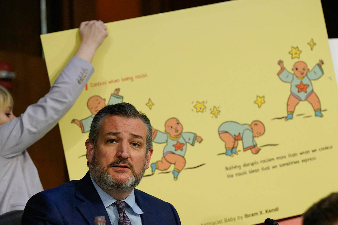 A staff member places a poster of page from a book by author Ibram X. Kendi behind Sen. Ted Cruz, R-Texas, as he questions Supreme Court nominee Ketanji Brown Jackson during her Senate Judiciary Committee confirmation hearing on Capitol Hill in Washington, Tuesday, March 22. (Alex Brandon / Associated Press)