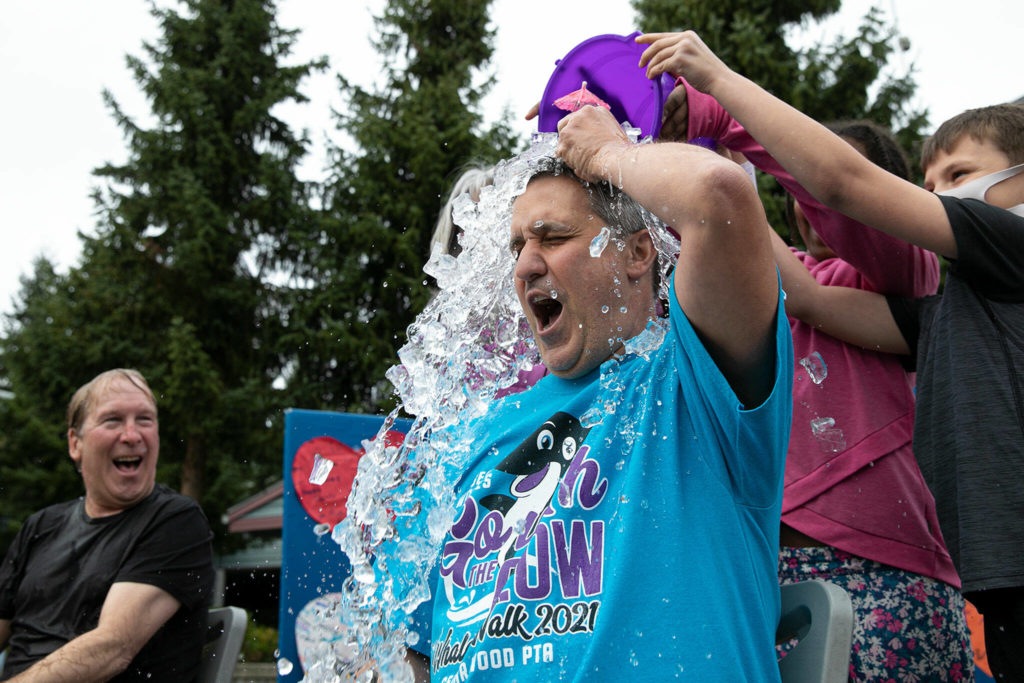 John Pappas, a fourth grade teacher, tries to protect himself with a cocktail umbrella to no avail. (Ryan Berry / The Herald)
