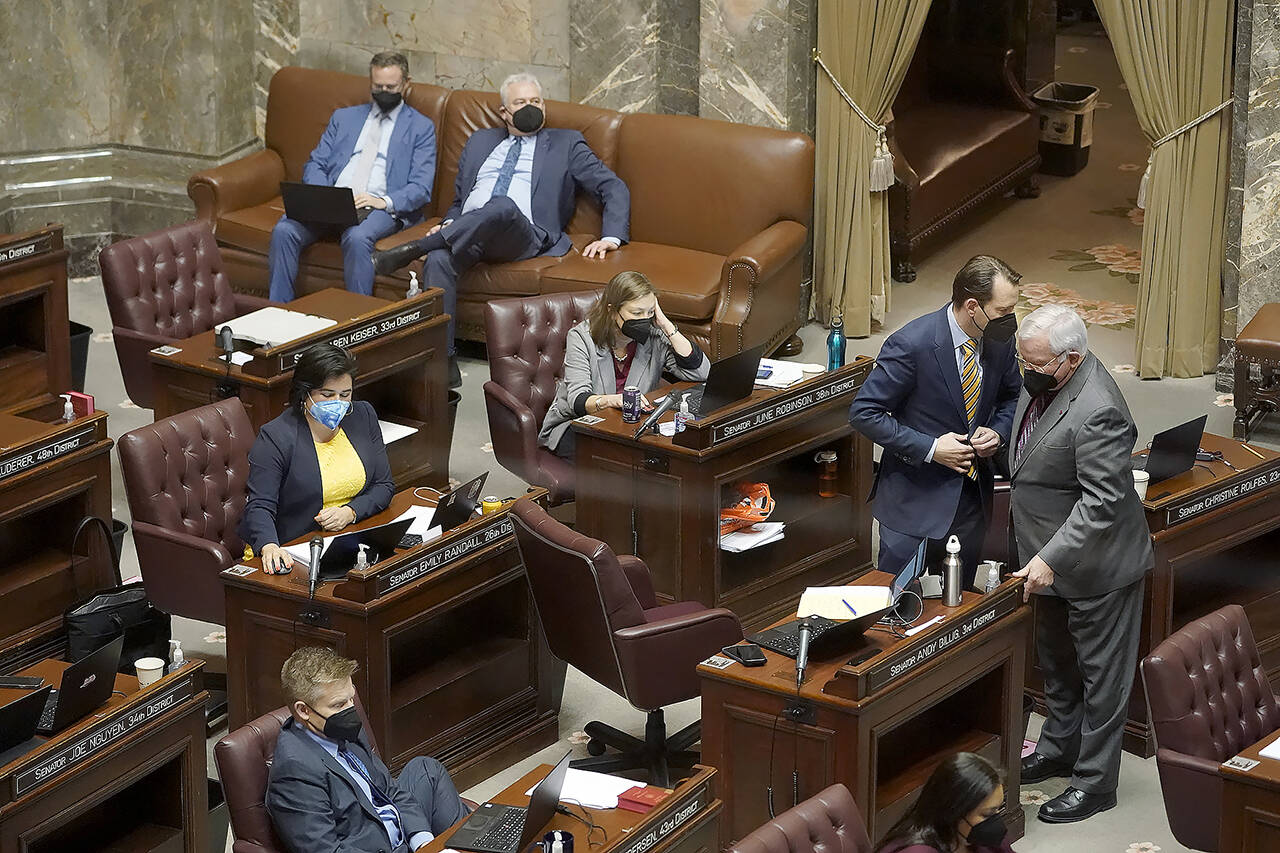 Sen. Andy Billig, D-Spokane, second from right, confers with Sen. Sam Hunt, D-Olympia, right, in front of Sen. June Robinson, D-Everett, on the Senate floor at the Capitol in Olympia on Feb. 15, 2022, during debate. (Ted S. Warren / Associated Press)