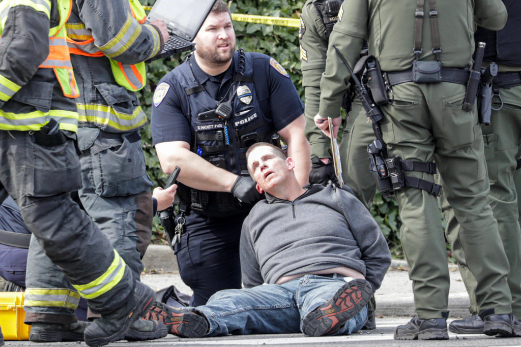 The suspect in the shooting of a police officer is held at 35th and Rucker Ave after a three car accident in Everett, Washington on March 25, 2022. (Kevin Clark / The Herald)
