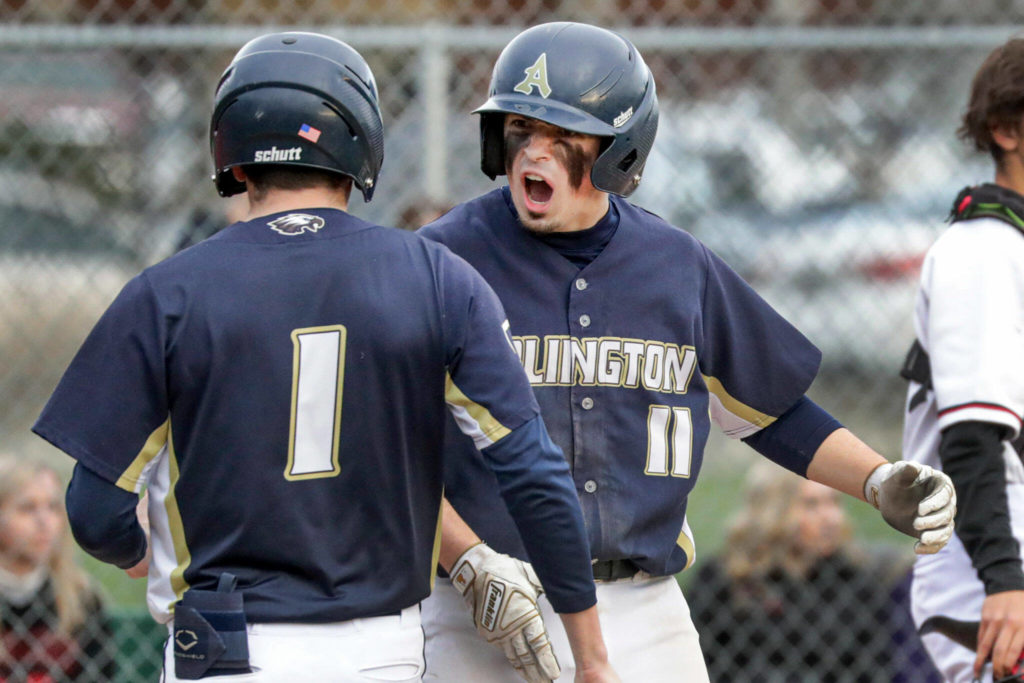 Arlington’s Aiden Green, left, and Arlington’s Trenton Lamie celebrate Lamie’s run against Snohomish Friday afternoon at Snohomish High School. The Eagles won 4-2. (Kevin Clark / The Herald)
