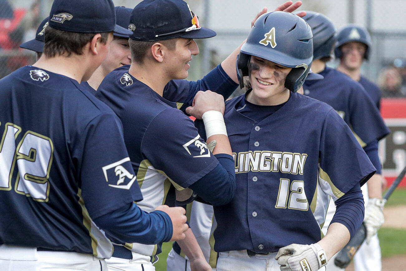 Arlington's Cooper McBride (12) is celebrated for his two-run home run in the 7th inning against Snohomish Friday afternoon at Snohomish High School in Snohomish, Washington on March 25, 2022. The Eagles won 4-2. (Kevin Clark / The Herald)