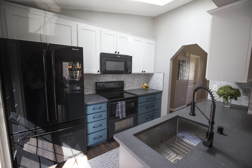 In Shelly Henderson’s kitchen, the bottom cabinets were painted blue to add a pop of color, while the cherry upper cabinets were painted white. A gray quartz countertop is complemented by a gray and white tile backsplash. (Andy Bronson)
