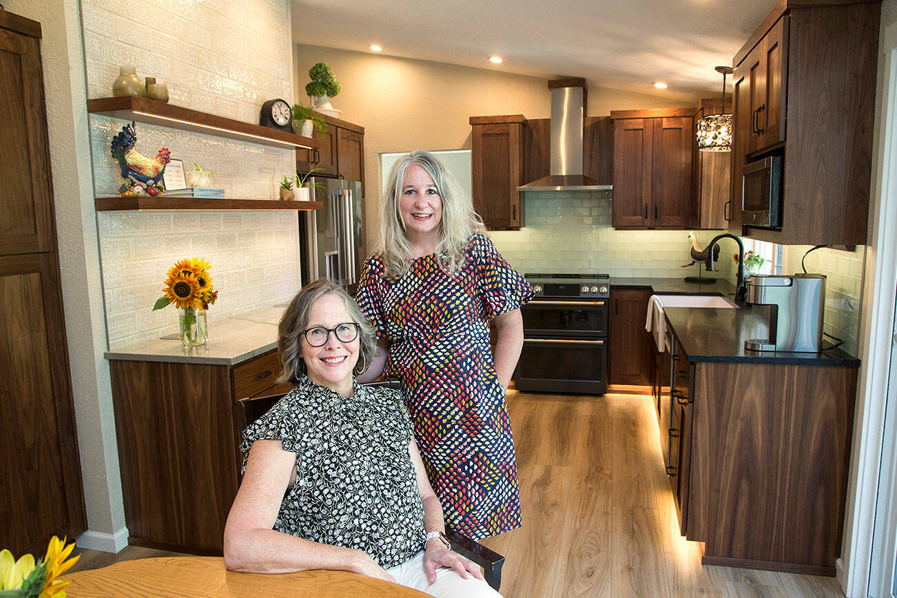 Mary Beth Kurtenbach (seated0 in her remodeled kitchen, designed by Lake Stevens' Distinctive Designs' Kelly DuByne, on Tuesday, Sept. 7, 2021 in Lake Stevens, Washington. The Kitchen features a Monet Inspired tile wall, floating shelves and toe kick lights. (Andy Bronson / The Herald)