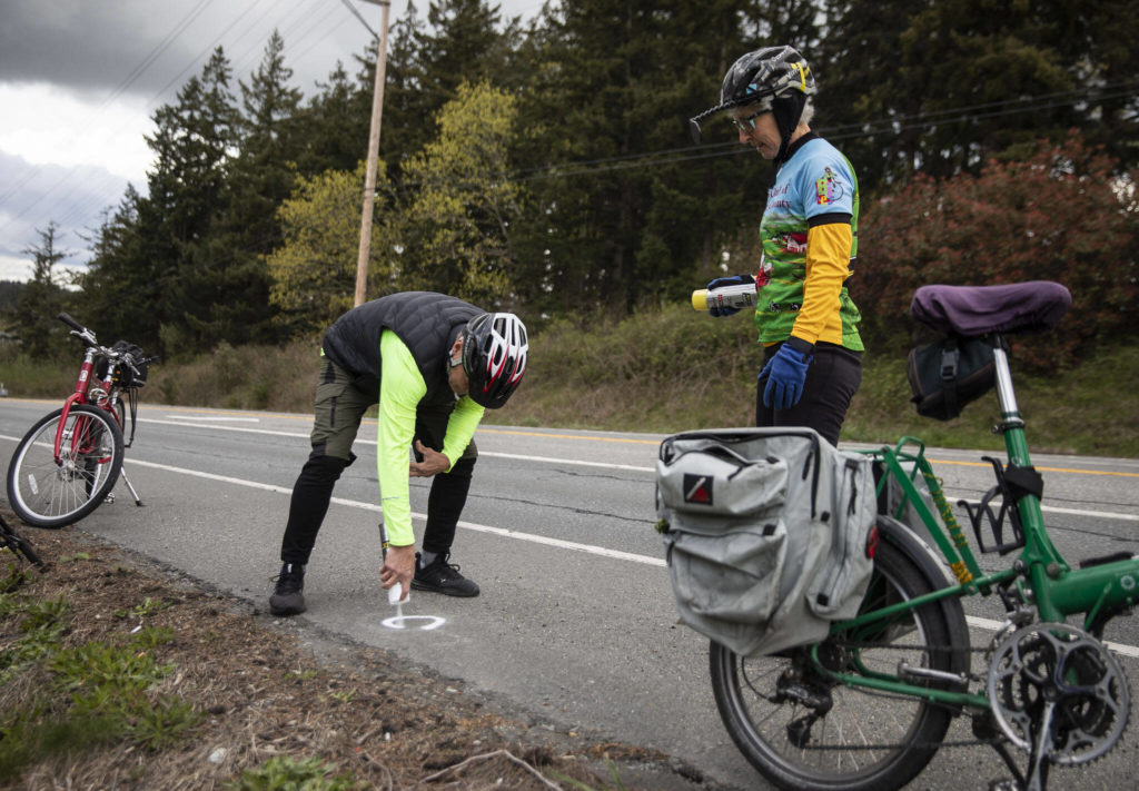 Steve Boskovich spray paints a Dan Henry directional mark along Highway 532 on Sunday, April 10, 2022 in Camano Island, Washington. (Olivia Vanni / The Herald)
