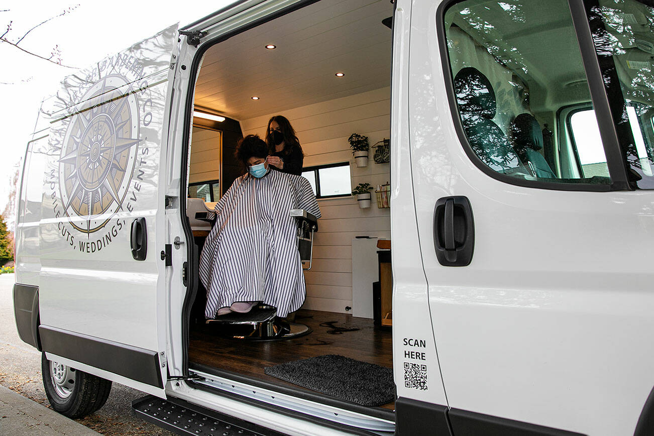 Alex Lewis, of Wanderer Barbering Co., cuts the hair of Anna Kincaid in the mobile hair studio that Lewis created last year on Saturday, March 26, 2022, in Everett, Washington. (Ryan Berry / The Herald)