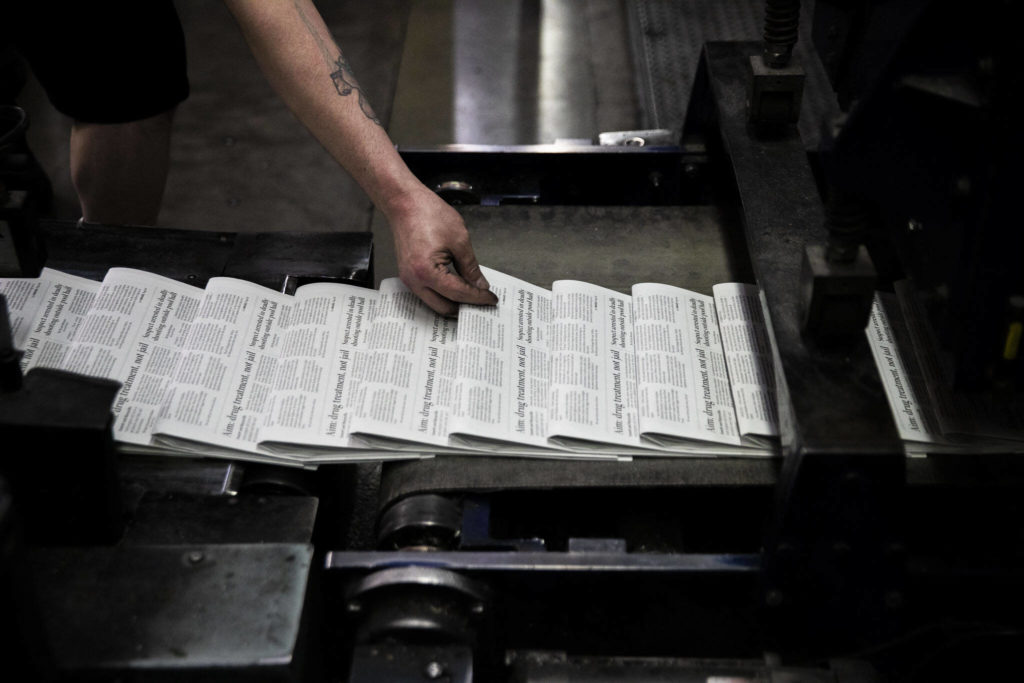 Mike Tullar grabs a copy of The Herald to check for quality at the press at Paine Field in Everett. (Olivia Vanni / The Herald)
