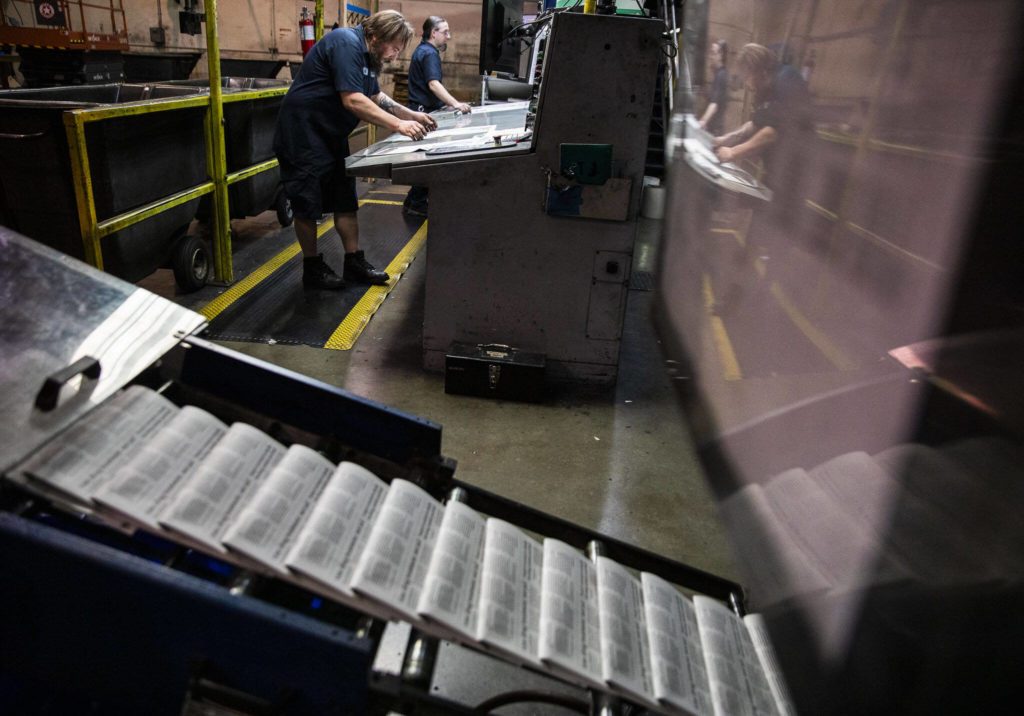 Mike Tullar and Alex Hanson examine Herald papers as they roll off the press in Everett. (Olivia Vanni / The Herald)
