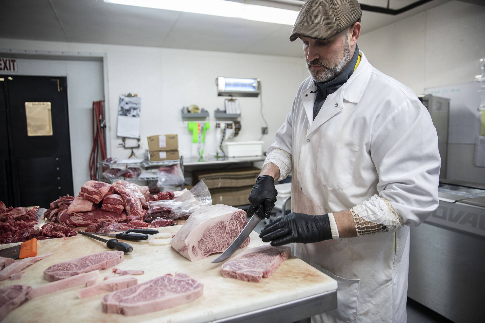 Sean Sanderson slices a Japanese Wagyu A5+ at EC Wilson Meat Co. in Lynnwood. A marbled steak sells for about $100 per pound. The beef is imported from Japan and comes with a certificate that tracks the animal’s lineage, place of birth and other details. (Olivia Vanni / The Herald)