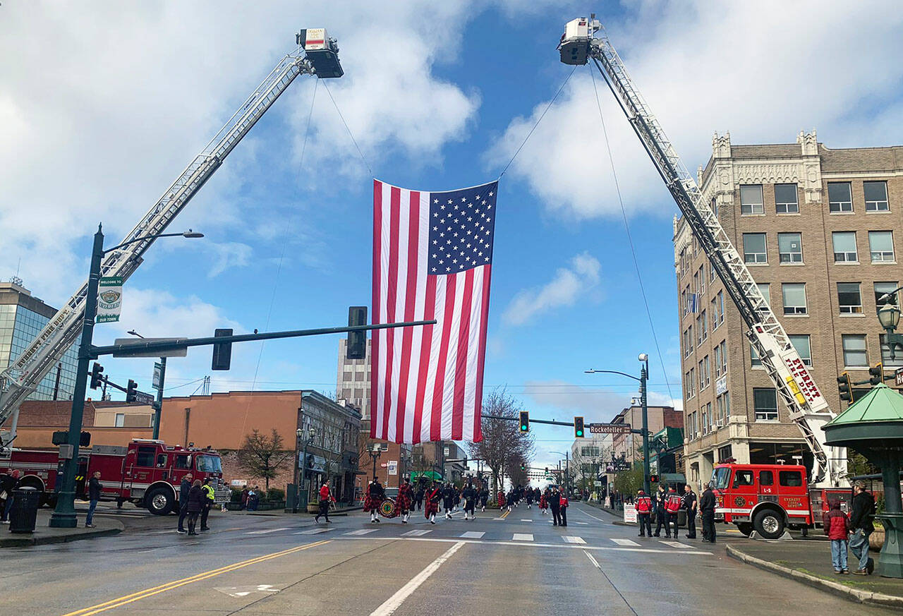 An American flag was hung over the passing motorcade honoring slain Everett police officer Dan Rocha on Monday in downtown Everett. (Jake Goldstein-Street / The Herald)