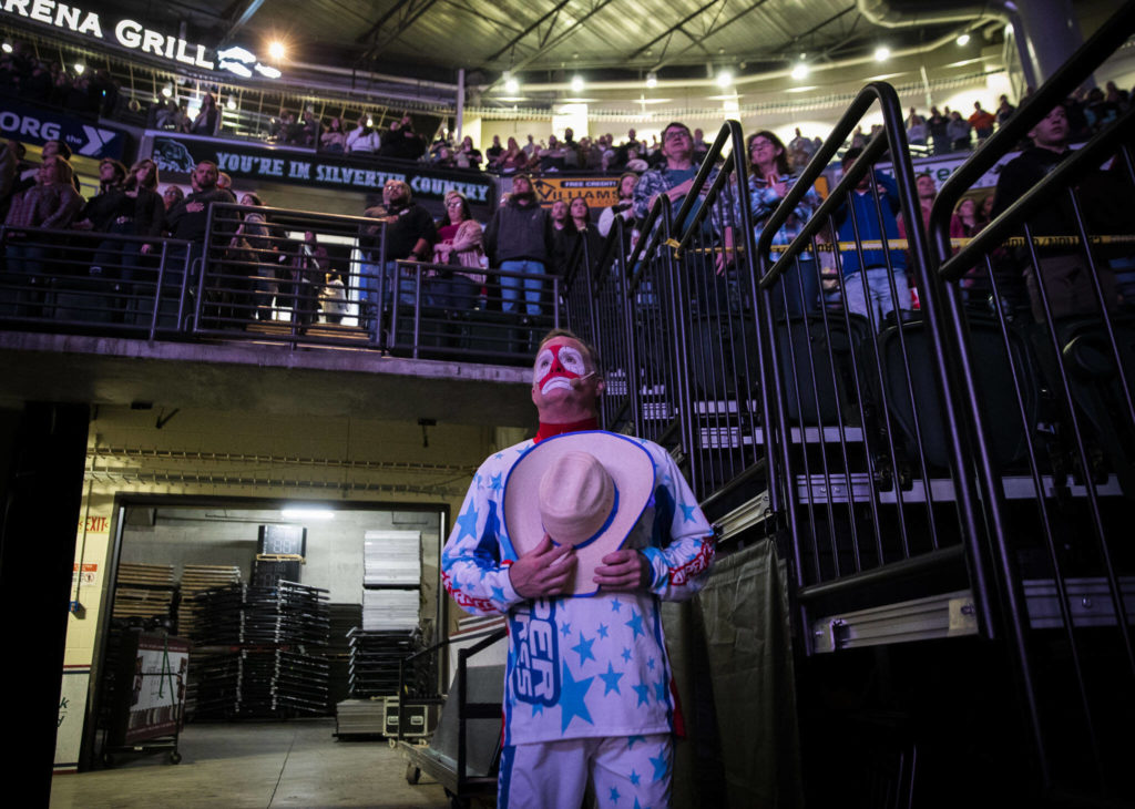 PBR rodeo entertainer Flint Rasmussen pauses for the National Anthem before entering the arena during the PBR Everett Invitational at Angel of the Winds Arena on Wednesday, April 6, 2022 in Everett, Washington. (Olivia Vanni / The Herald)
