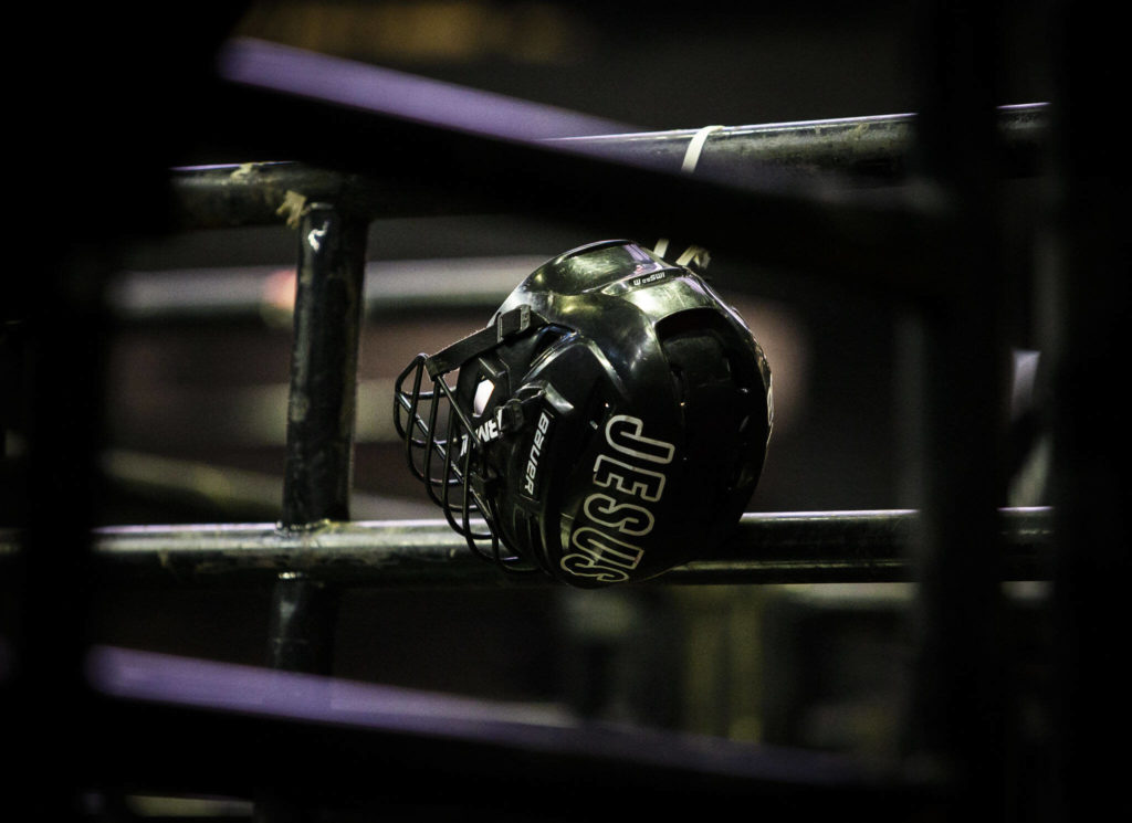 A bull riding helmet with the word “JESUS” hangs on a railing during the PBR Everett Invitational at Angel of the Winds Arena on Wednesday, April 6, 2022 in Everett, Washington. (Olivia Vanni / The Herald)
