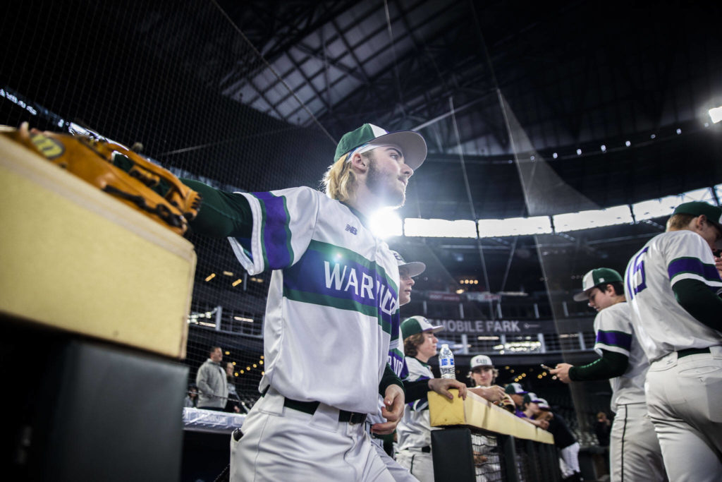 Edmonds-Woodway’s Jonah Brower grabs his glove as he runs onto the field Friday night at T-Mobile Park, where the Warriors faced Kentwood as part of the High School Baseball Classic. (Olivia Vanni / The Herald)
