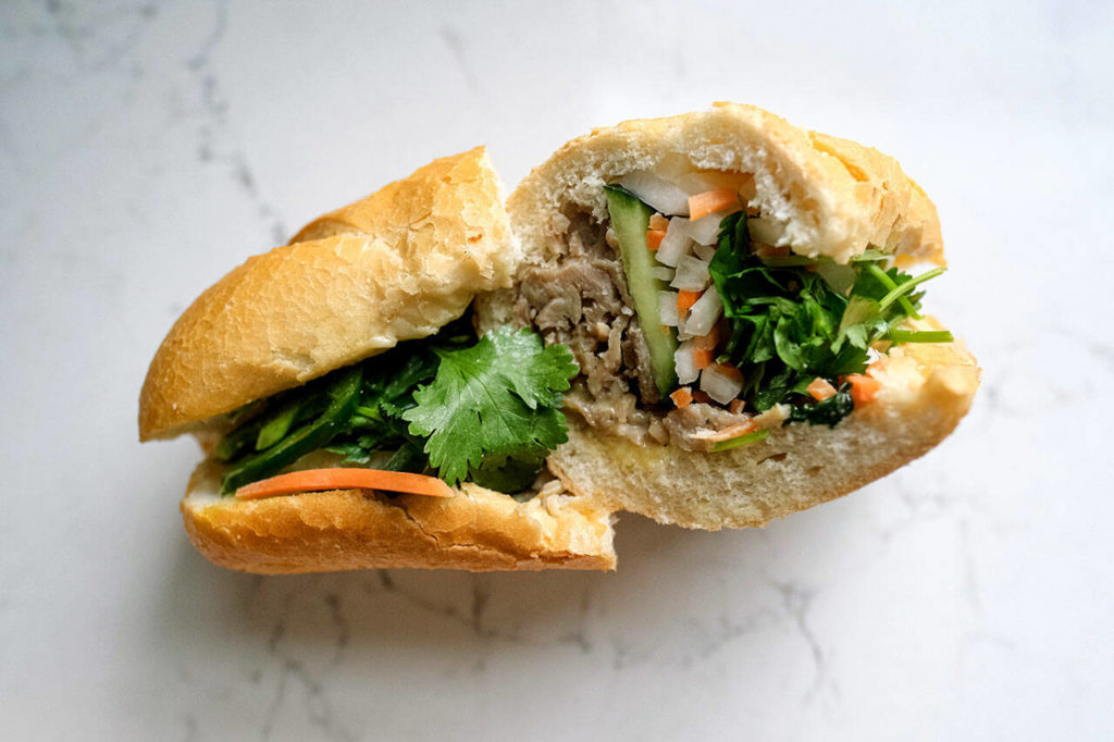 Bánh mì, a traditional Vietnamese sandwich, starts with a short, crispy baguette stuffed with marinated meats like pork and chicken (or tofu), then it gets crunchified with pickled daikon, carrots, cucumbers, jalapeno and cilantro. (Taylor Goebel / The Herald)
