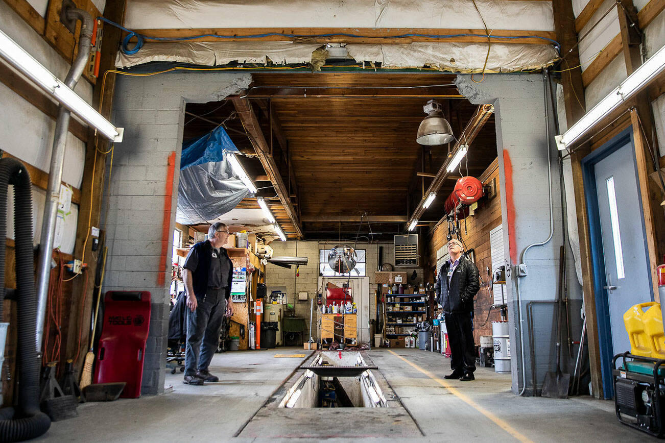 Sultan School District Superintendent Dan Chapik, right, and lead mechanic Dan Erdman look up at a large missing piece of wall that was taken out to fit the busses inside as they got taller on Wednesday in Sultan. Voter approval of a capital levy would fund a new transportation facility and give the district access to nearly $4 million in state funding. (Olivia Vanni / The Herald)