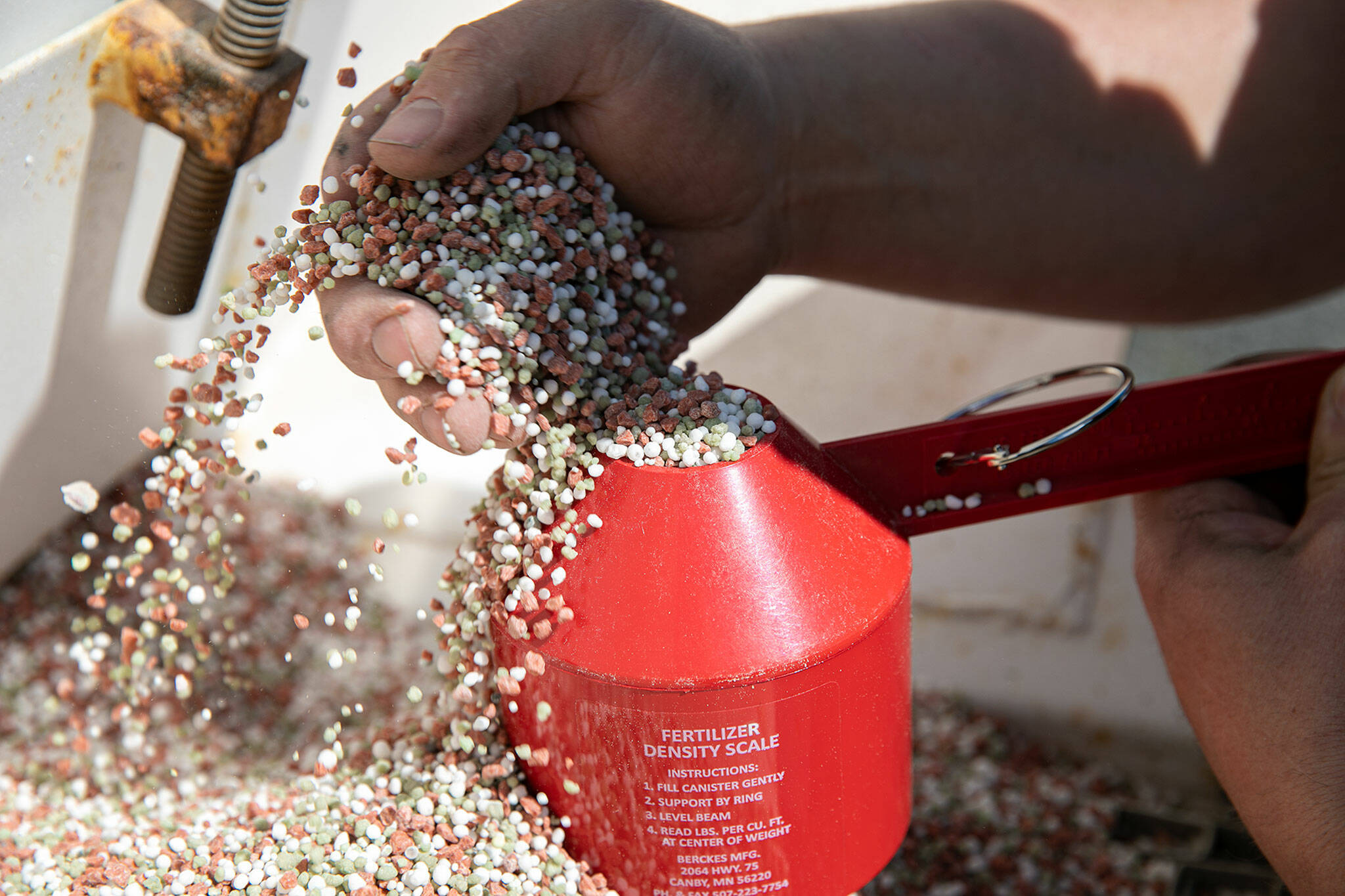 Andrew Albert measures the density of his fertilizer using a specialized scale Friday at his farm in Arlington. Fertilizer prices have skyrocketed in the past year. (Ryan Berry / The Herald)
