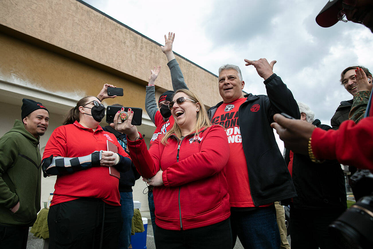 Carissa Hahn, center, holds her phone while livestreaming a unionization vote as Verizon workers and supporters begin to celebrate votes tallied in favor of unionizing Friday, April 15, 2022, in Everett, Washington. (Ryan Berry / The Herald)