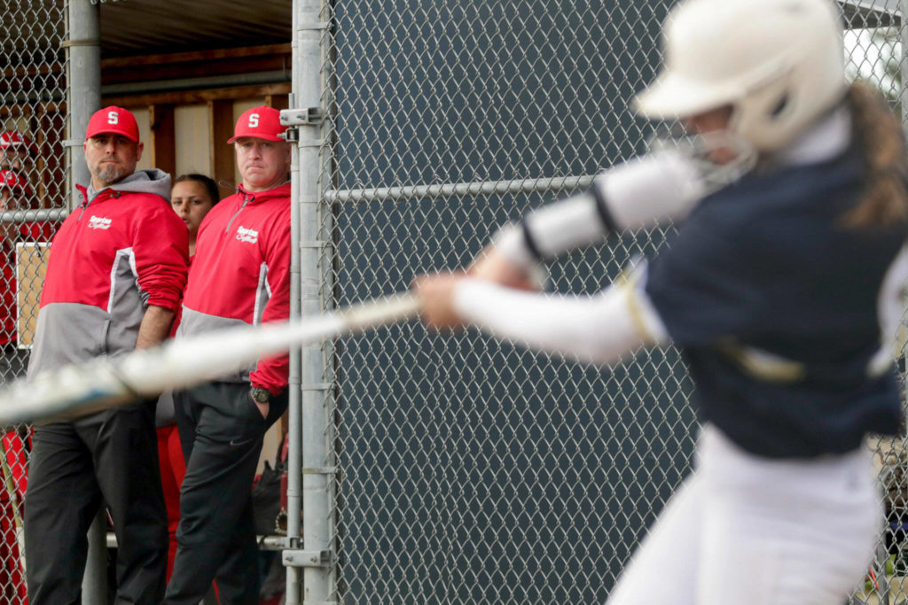 Stanwood assistant Chris Songhurst (left) and head coach Patrick Ryan (second from left) watch Arlington’s Reagan Ryan bat during a game Monday afternoon at Arlington High School. (Kevin Clark / The Herald)
