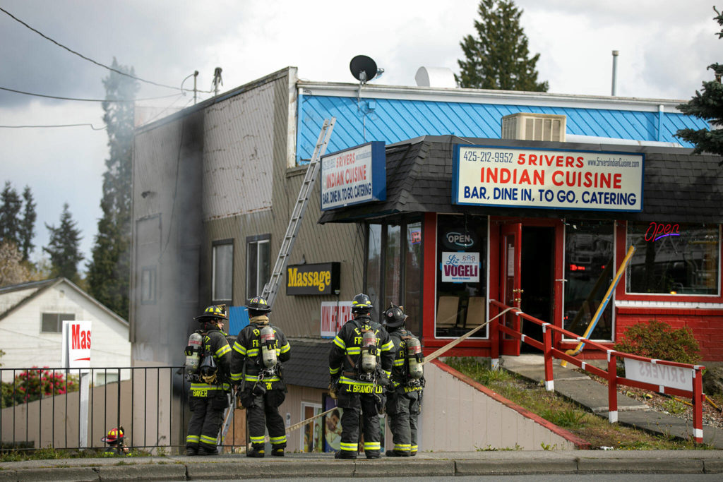Smoke can be seen coming out of a lower level garage behind 5 Rivers Indian Cuisine on Evergreen Way Thursday, April 13, 2022, in Everett, Washington. (Ryan Berry / The Herald)
