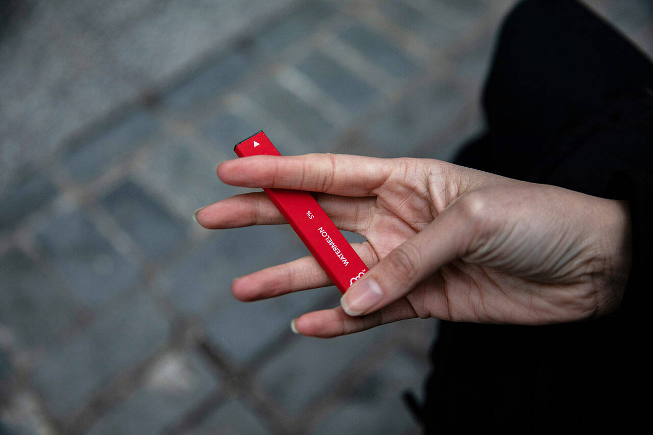 A woman holds a Puff Bar flavored disposable vape device in New York in January, 2020. The Food and Drug Administration says it will soon begin cracking down on vaping companies that have used a now-closed loophole to escape federal oversight, including the company behind a line of fruit-flavored e-cigarettes that have become the top choice among teenagers. Under a new law taking effect April 14, the FDA can regulate e-cigarettes and similar products that use synthetic nicotine. (Marshall Ritzel / Associated Press)
