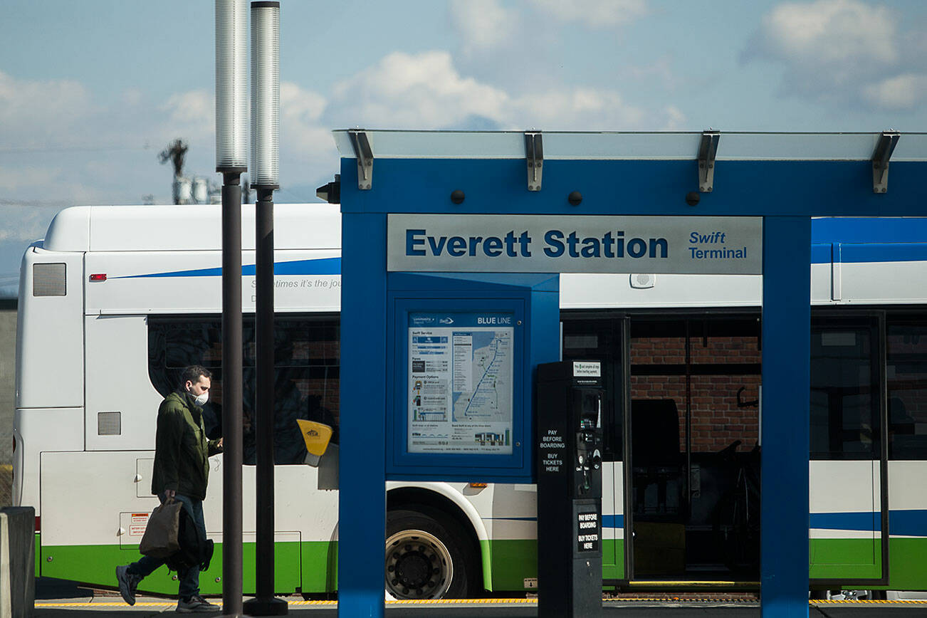 A man wearing a face mask walks toward the rear door of a Community Transit bus at the Everett Station on Friday, March 20, 2020 in Everett, Wa. (Olivia Vanni / The Herald)