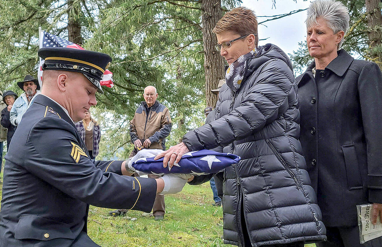 Sgt. Austen Poland, of the Oregon National Guard, presents an American flag to Kylie Tigard, cousin to Tamera “Tammy” Lee Tigard, during a burial in Sutherlin, Oregon, on Monday. The service with full military honors was the final chapter for the U.S. Army specialist whose death remained a mystery for more than four decades. (The News-Review)