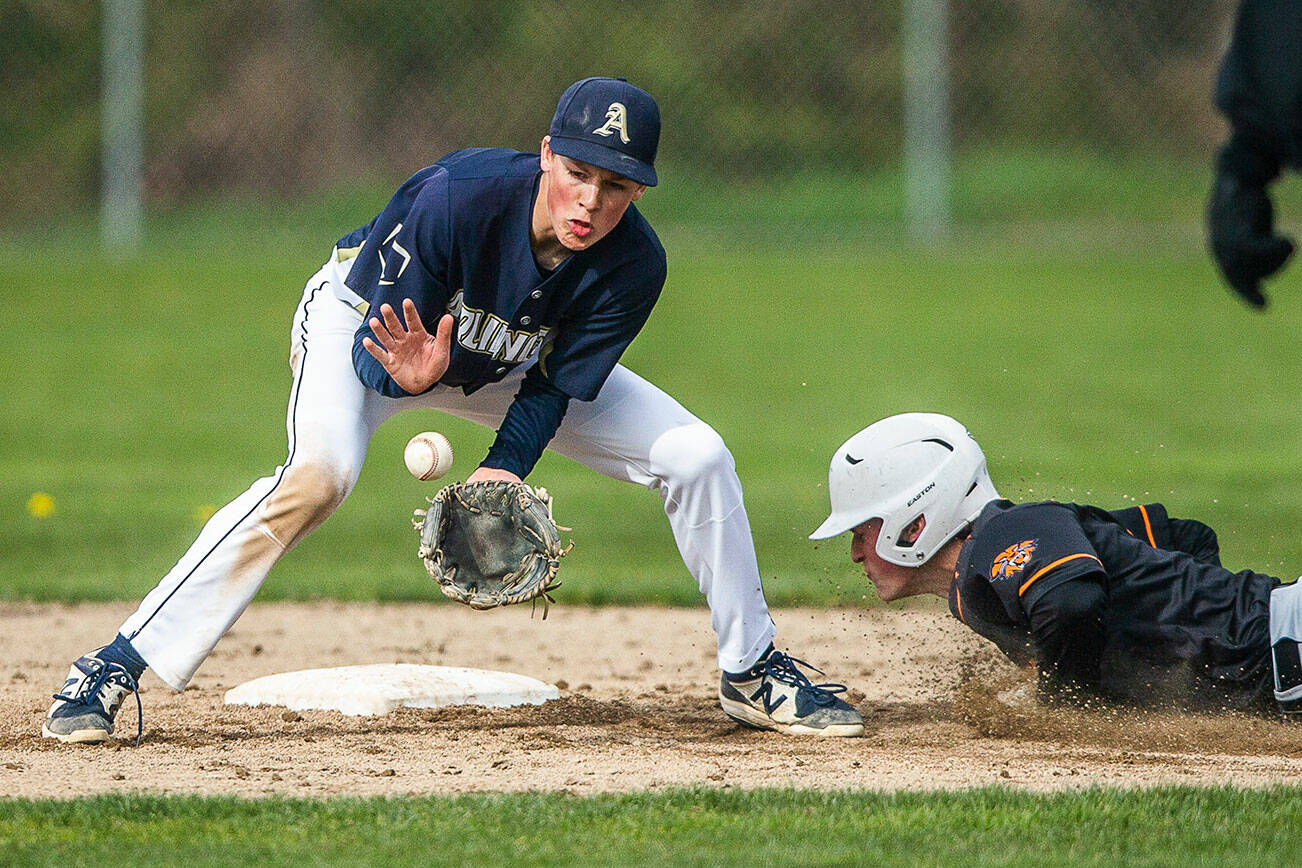 Arlington’s Tyler Rusko catches a ground ball while Monroe’s Kody Edelbrock slides into second base during the game on Thursday, April 21, 2022 in Arlington, Washington. (Olivia Vanni / The Herald)