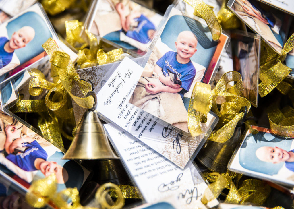 Small golden bells with thank you notes attached sit on a table for friend and family to grab to join Peyton in the ringing of her end of chemotherapy bell on Saturday, April 23, 2022 in Bothell, Washington. (Olivia Vanni / The Herald)
