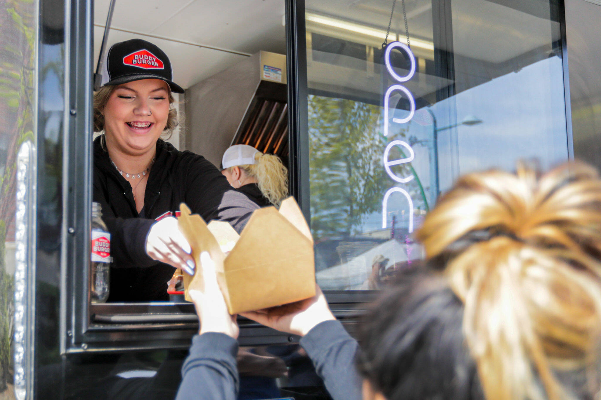 Tiffany Armstrong hands over an order from the Buddy Burger food trailer Saturday morning in Everett. (Kevin Clark / The Herald)
