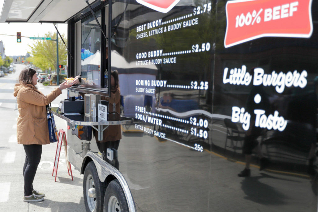 Kimi Nolte receives her order from the Buddy Burger food trailer Saturday morning in Everett. (Kevin Clark / The Herald)
