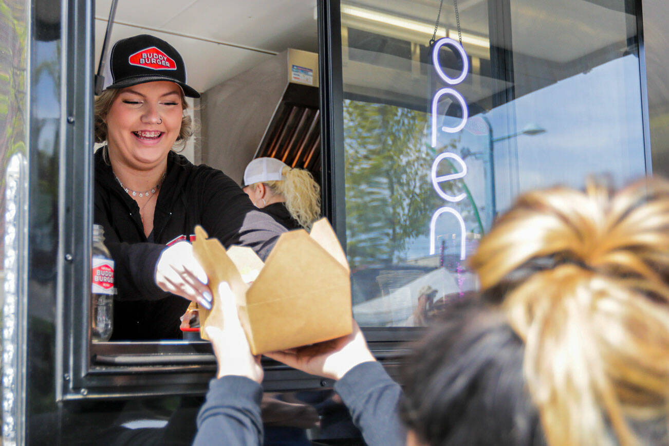 Tiffany Armstrong hands over an order from the Buddy Burger food trailer Saturday morning in the Everett, Washington on April 23, 2022. (Kevin Clark / The Herald)
