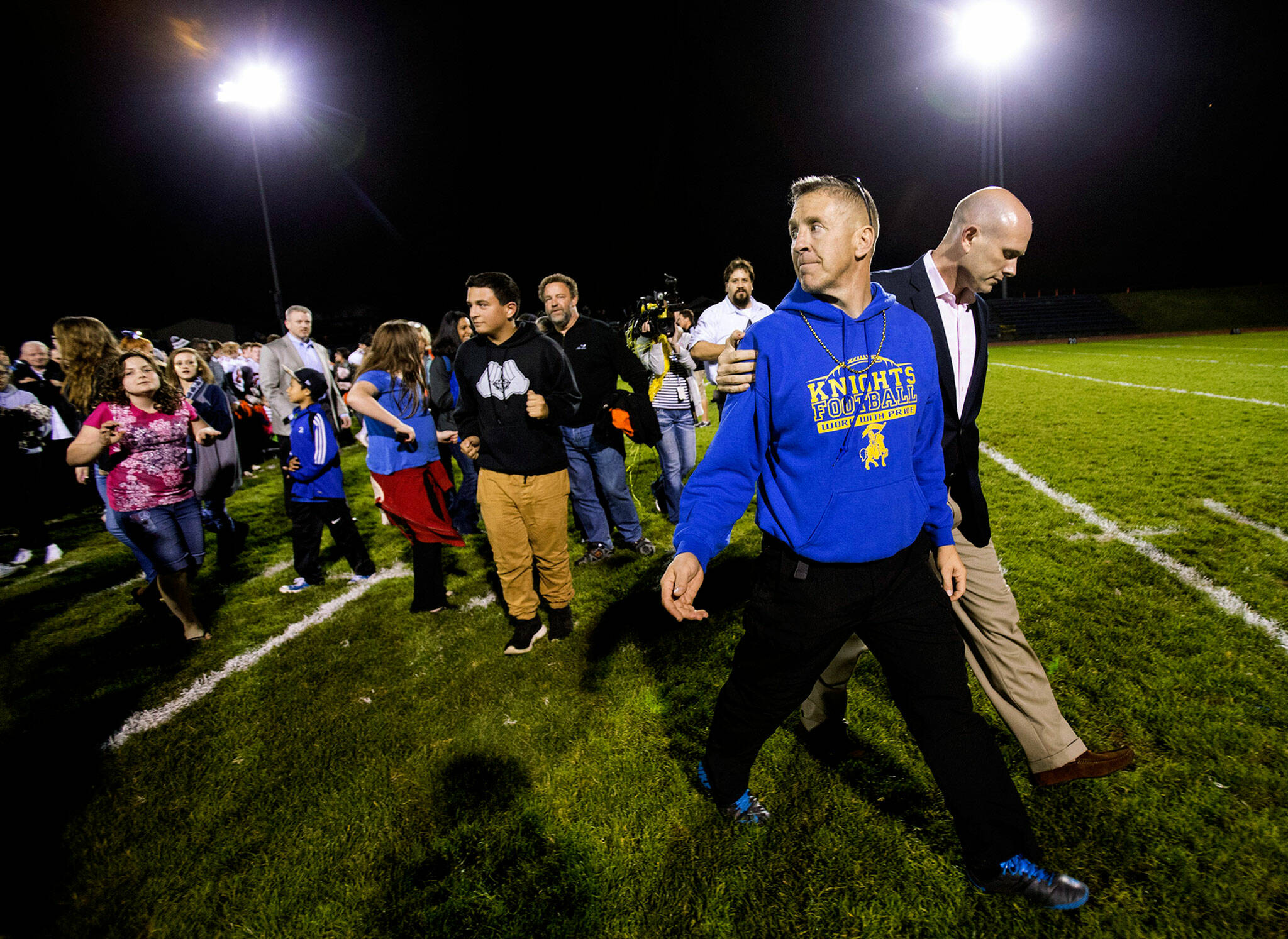 Bremerton High assistant football coach Joe Kennedy (front) walks off the field with his lawyer on Oct. 16, 2015, after praying at the 50-yard line following a football game in Bremerton. After losing his coaching job for refusing to stop kneeling in prayer with players and spectators on the field immediately after football games, Kennedy will take his arguments before the U.S. Supreme Court on Monday, saying the Bremerton School District violated his First Amendment rights by refusing to let him continue praying at midfield after games. (Lindsey Wasson/The Seattle Times via AP, File)