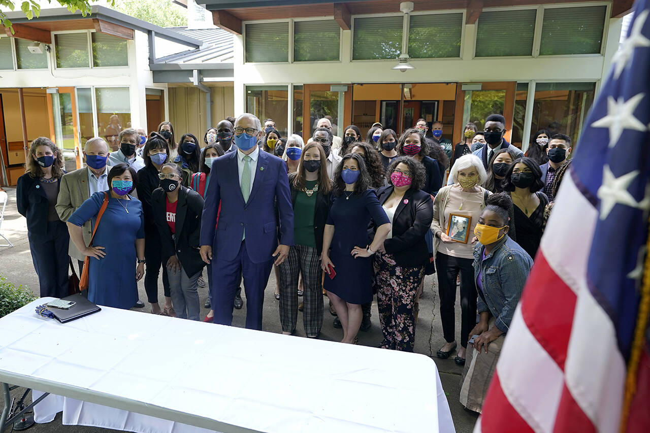 Washington Gov. Jay Inslee (center) after he signed a bill into law in Tukwila on May 4, 2021, that levies a new capital gains tax on high-profit stocks, bonds and other assets for some residents of Washington. (AP Photo/Ted S. Warren, file)