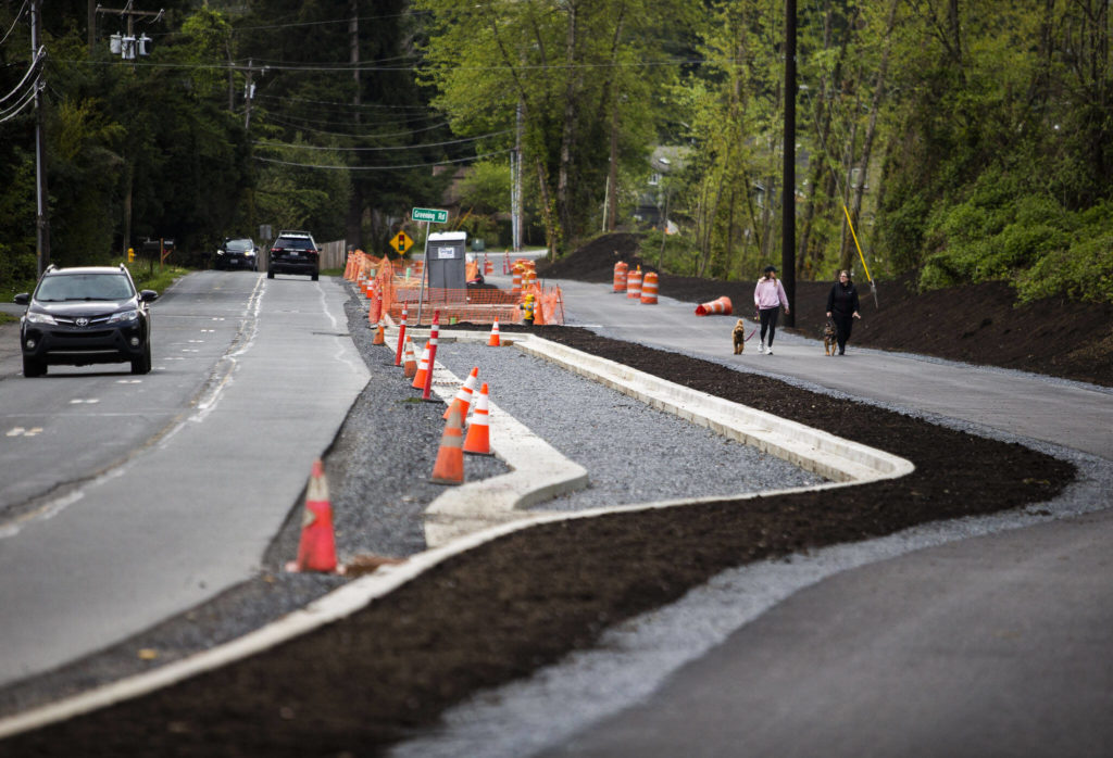 Traffic moves along Filbert Drive next to pedestrians walking along a new section of the North Creek Regional Trail. (Olivia Vanni / The Herald)

