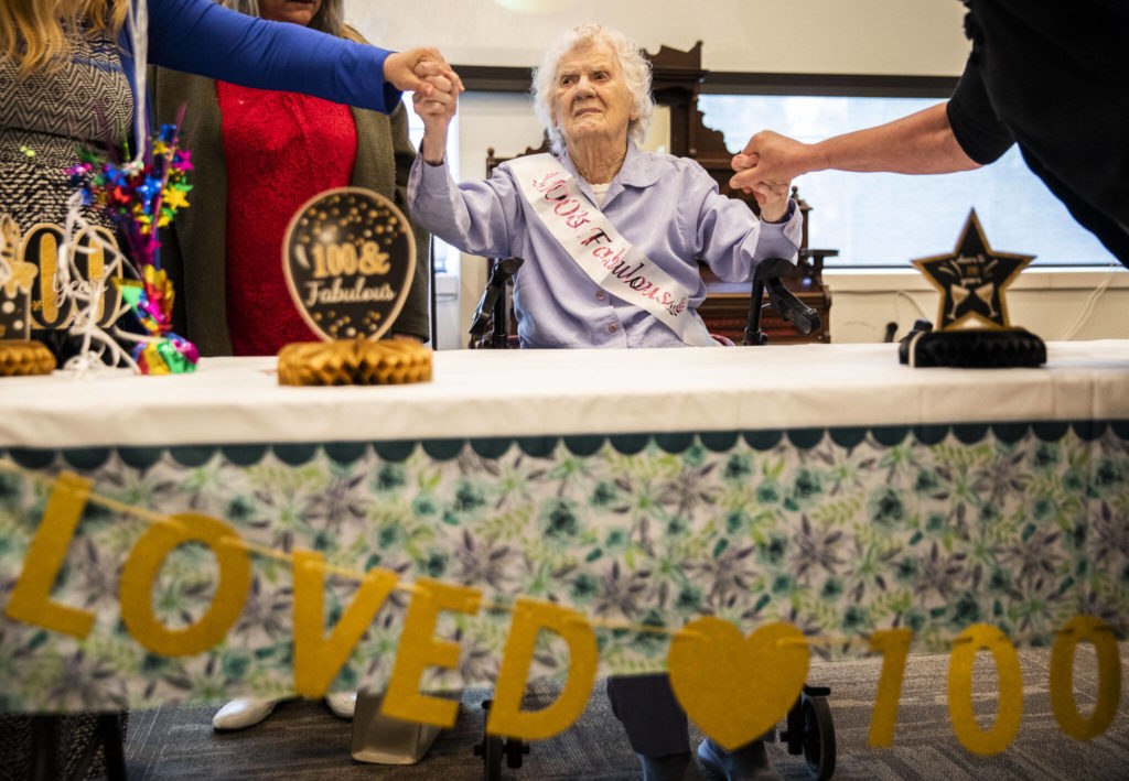 Ferne Ullestad holds family members’ hands while she sits are her table during her 100th birthday celebration Saturday. (Olivia Vanni / The Herald)
