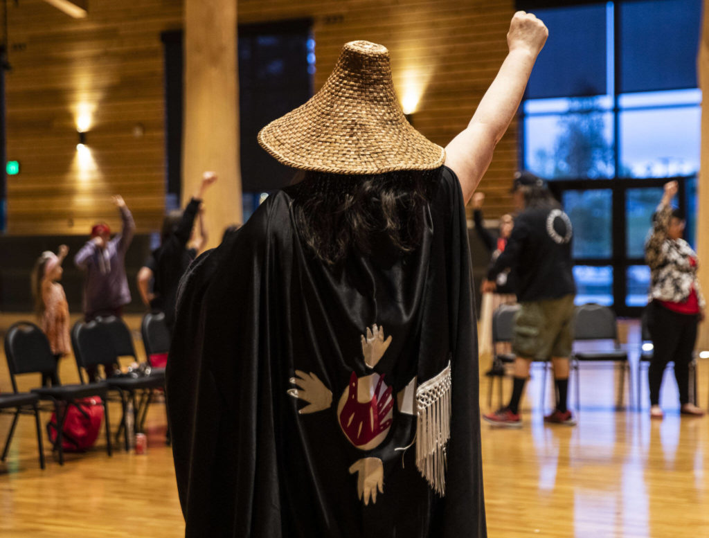 People raise their fists in support while listening to personal stories shared during a MMIW candlelight vigil at the Tulalip Gathering Hall on Thursday in Tulalip. (Olivia Vanni / The Herald)
