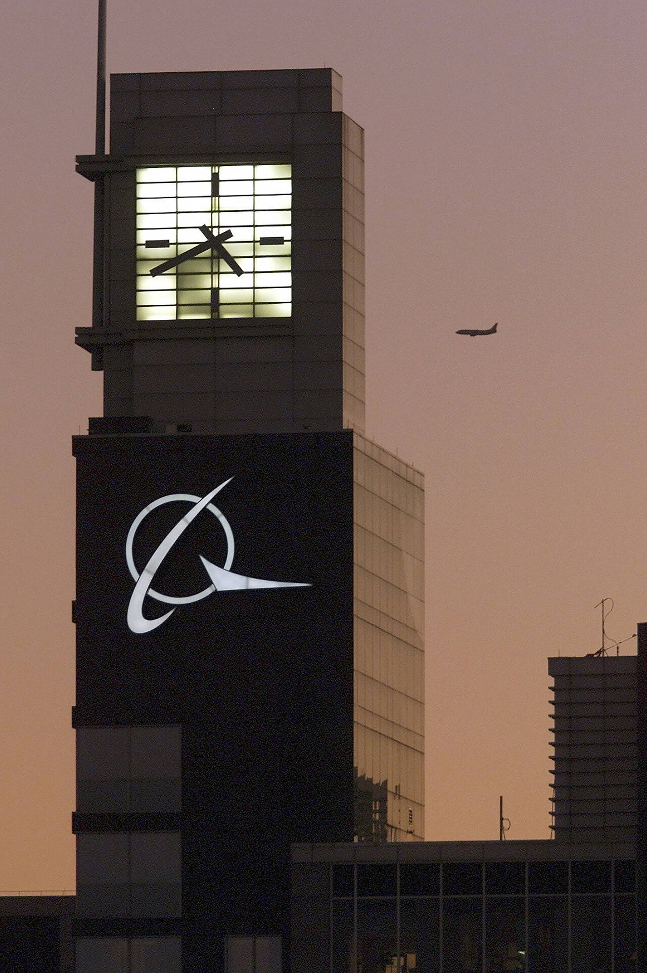 An airplane flies past the Boeing logo on the company’s headquarters in Chicago in 2001. The company is expected to move its headquarters from Chicago to the Washington, D.C. area. (AP Photo/Ted S. Warren, File)