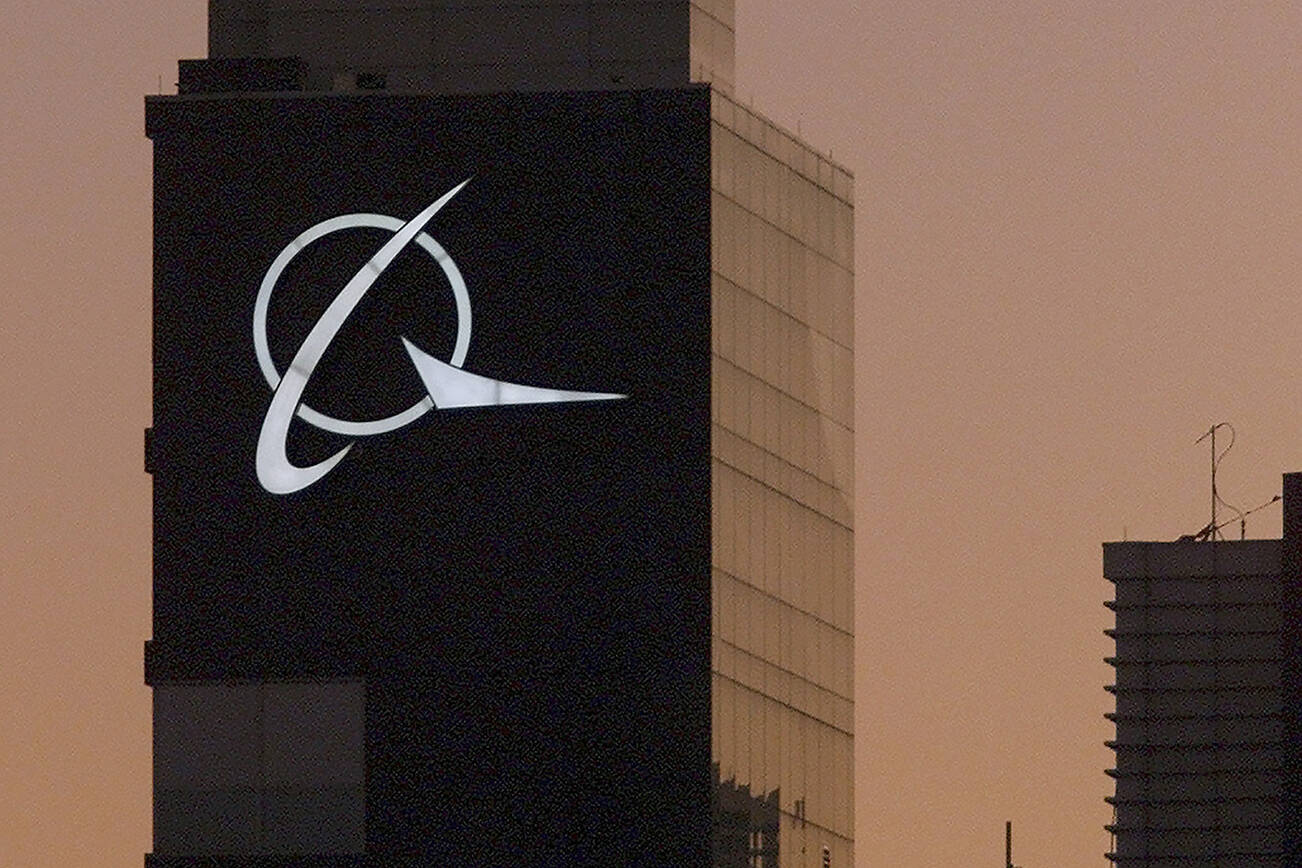 FILE - An airplane flies past the Boeing logo on the company's headquarters in Chicago, on Thursday, Dec. 20, 2001. Boeing Co., a leading defense contractor and one of the world's two dominant manufacturers of airline planes, is expected to move its headquarters from Chicago to the Washington, D.C., area, according to two people familiar with the matter. The decision could be announced as soon as later Thursday, May 5, 2022, according to one of the people. (AP Photo/Ted S. Warren, File)