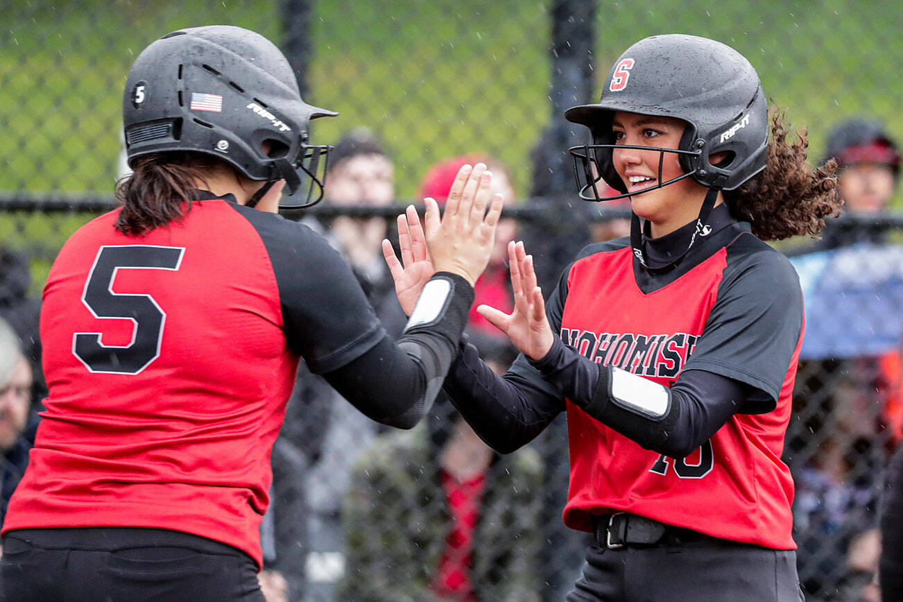 Snohomish's Alli Wilson, left, and welcomes teammate Emma Hansen to the plate, scoring a run against Cascade High School Thursday afternoon at Phil Johnson Ballfields in Everett, Washington on May 5, 2022. The Panthers won 9-3.  (Kevin Clark / The Herald)