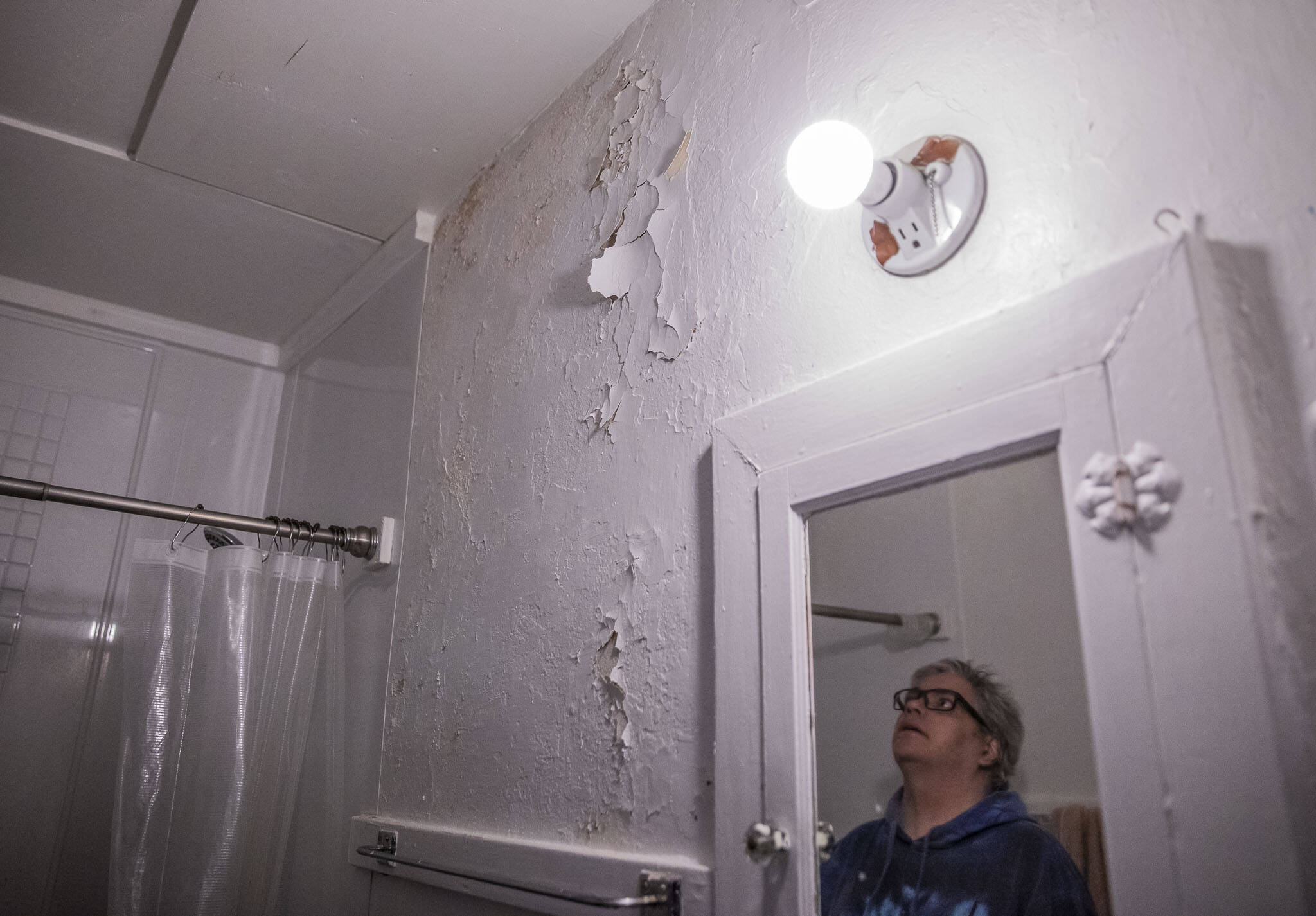 Steve Texieira looks up at peeling paint on the wall of his bathroom where water has leaked down from the apartment above. (Olivia Vanni / The Herald)