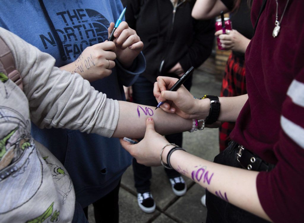 North Middle School students write “no means no” on their arms during a walkout on Monday. (Olivia Vanni / The Herald)
