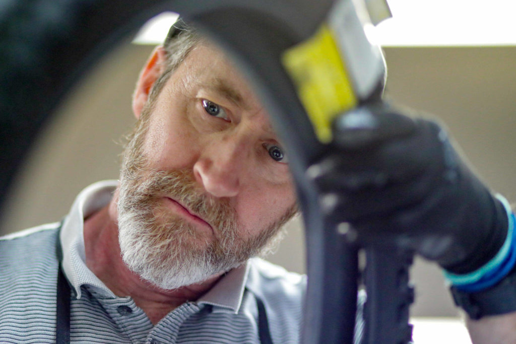 Jeff Austin checks a tire Tuesday at Sharing Wheels Community Bike Shop in Everett. The nonprofit is hosting weekly work parties to clean and repair used kids bikes for refugee families. (Kevin Clark / The Herald)
